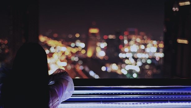Woman enjoying with night city view from the balcony