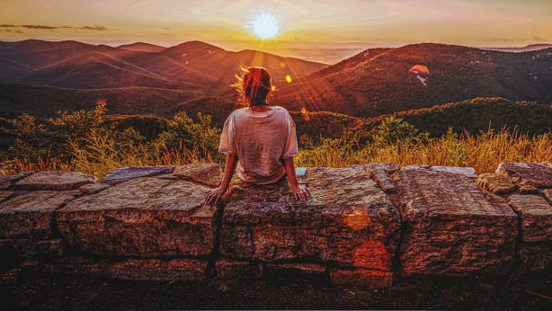 View of woman sees sunset over blue ridge mountains from skyline